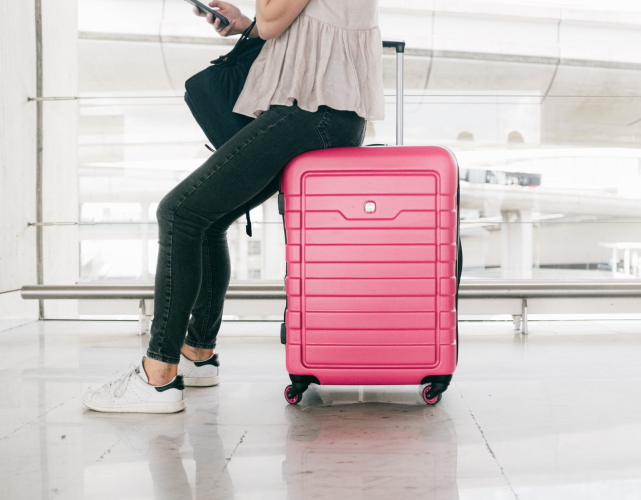 traveler sitting on a big pink suitcase