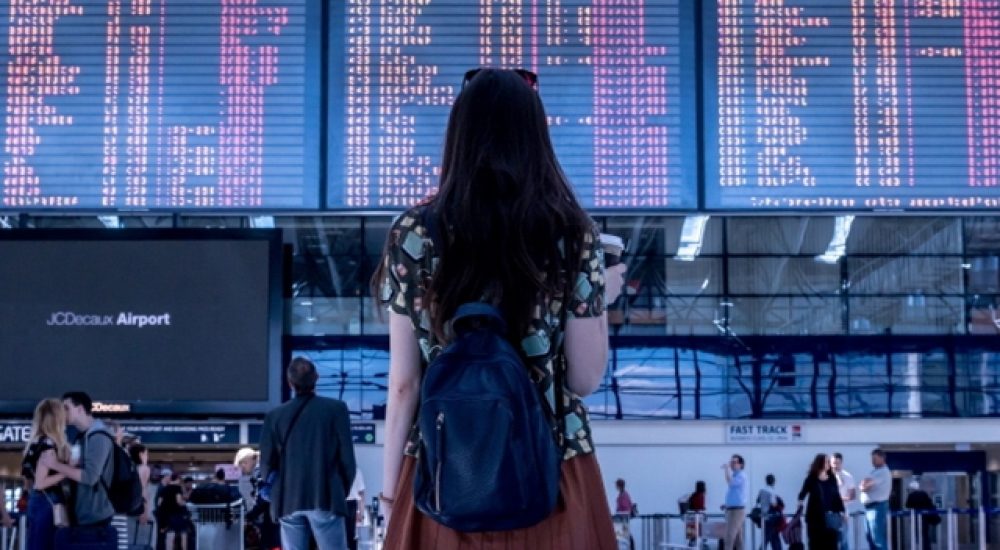 jeune fille debout devant affichage aéroport